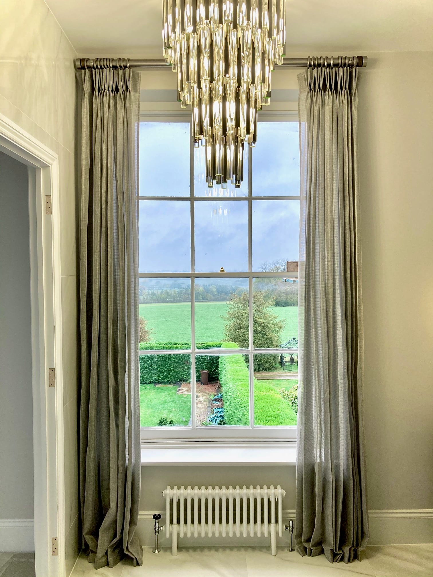 Whaddon Hall window detail — silver-grey curtains over countryside view