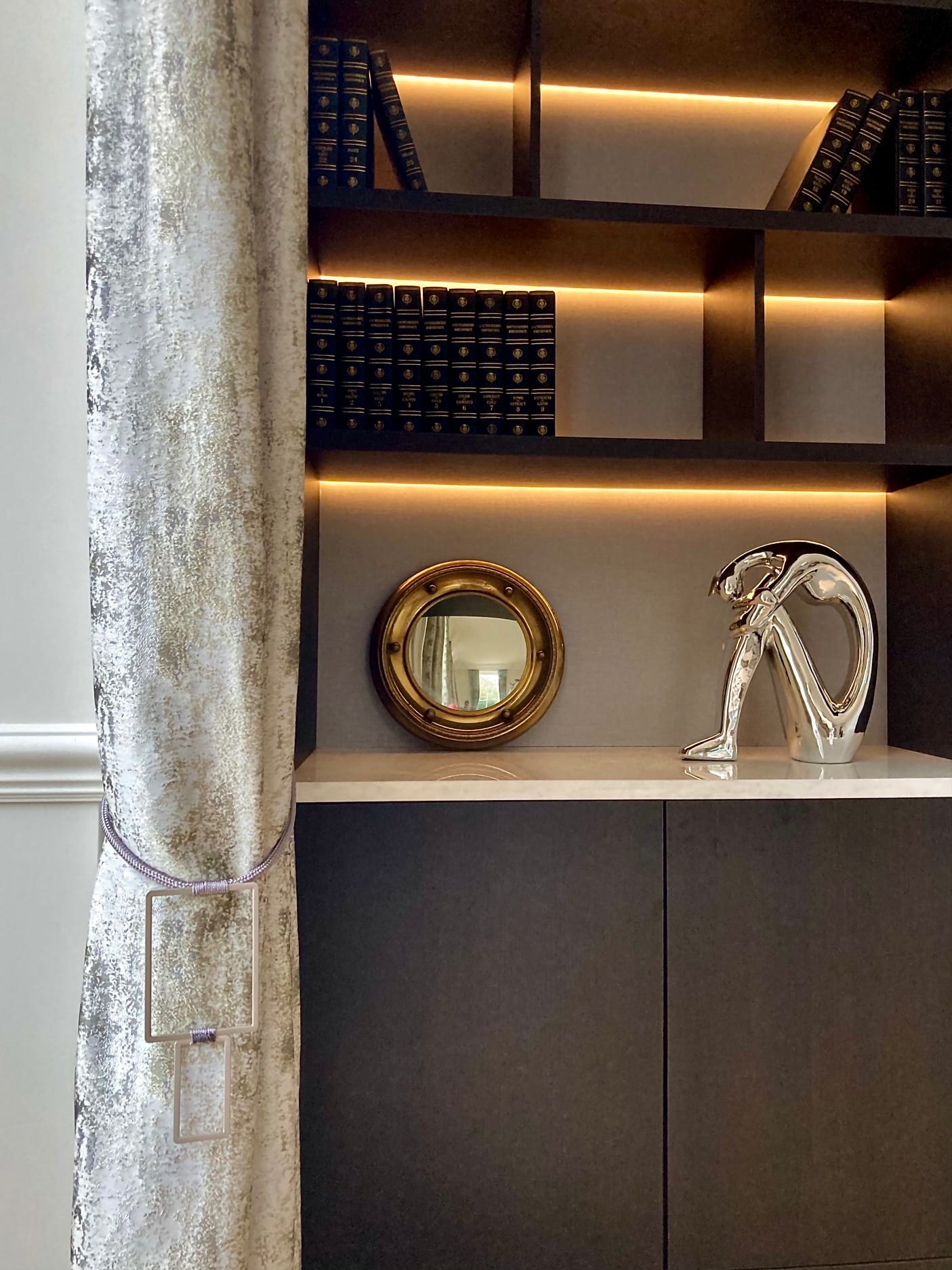 Whaddon Hall styled bookshelves with porthole mirror and art-deco figure