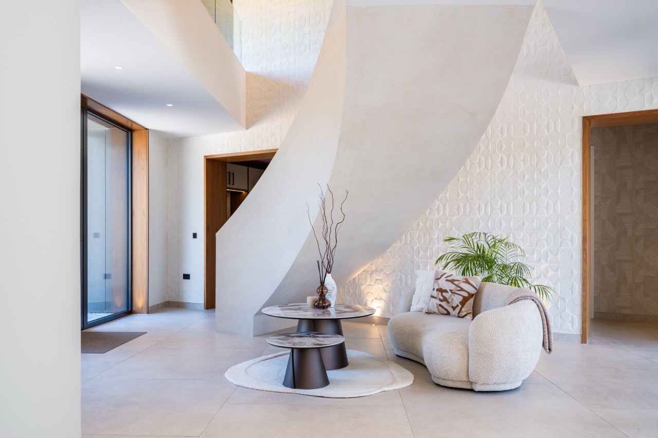 Queens Orchard reception hall with sculptural spiral staircase and curved bouclé sofa