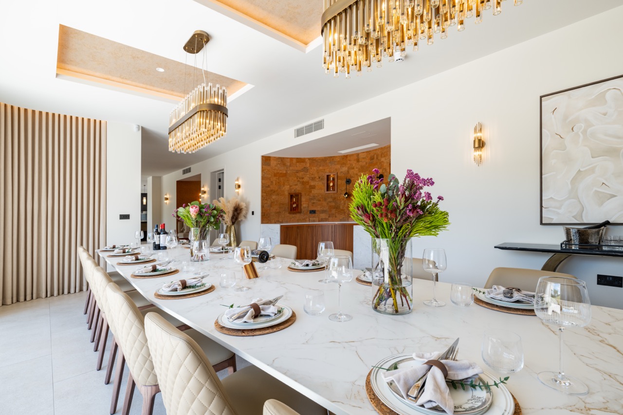 Queens Orchard dining table set beneath brass chandeliers