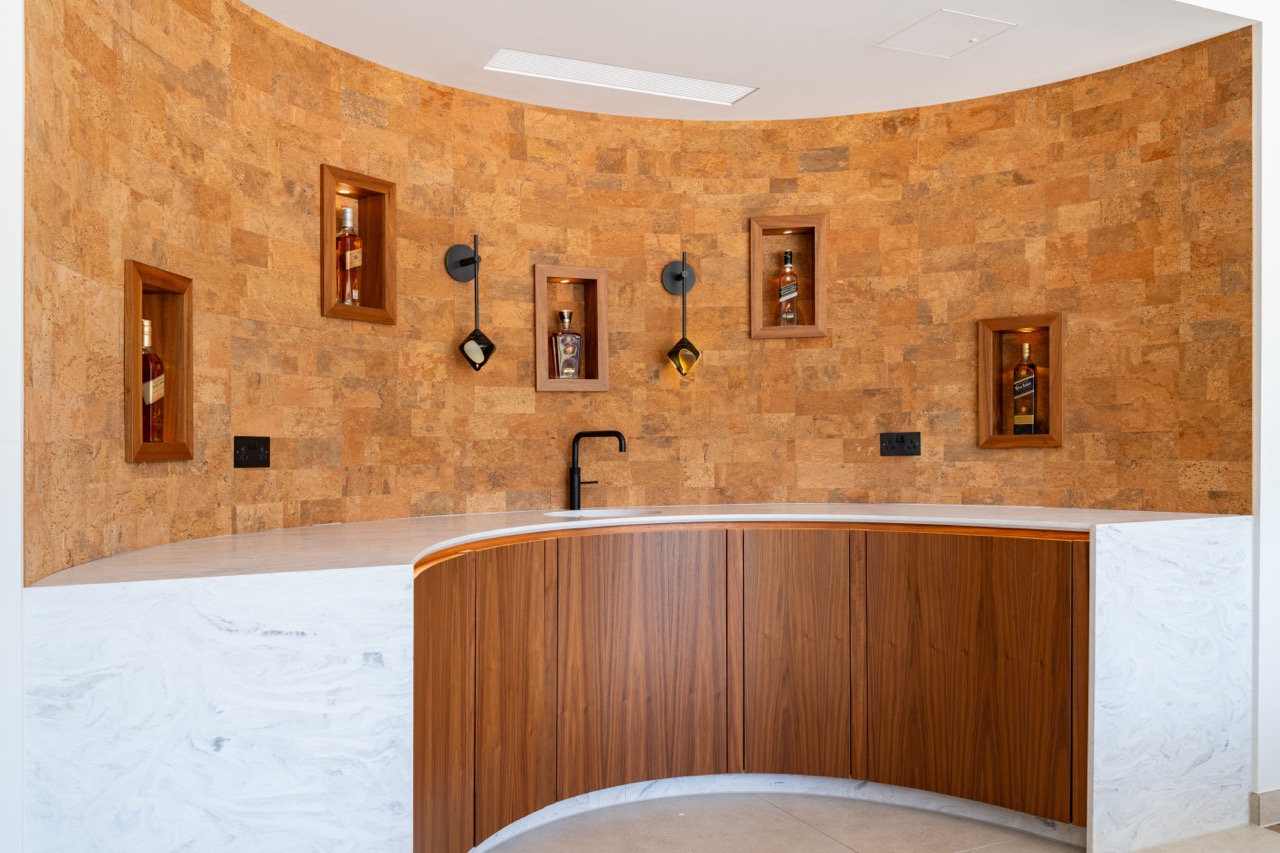 Queens Orchard curved drinks bar with cork-clad wall and lit whisky niches