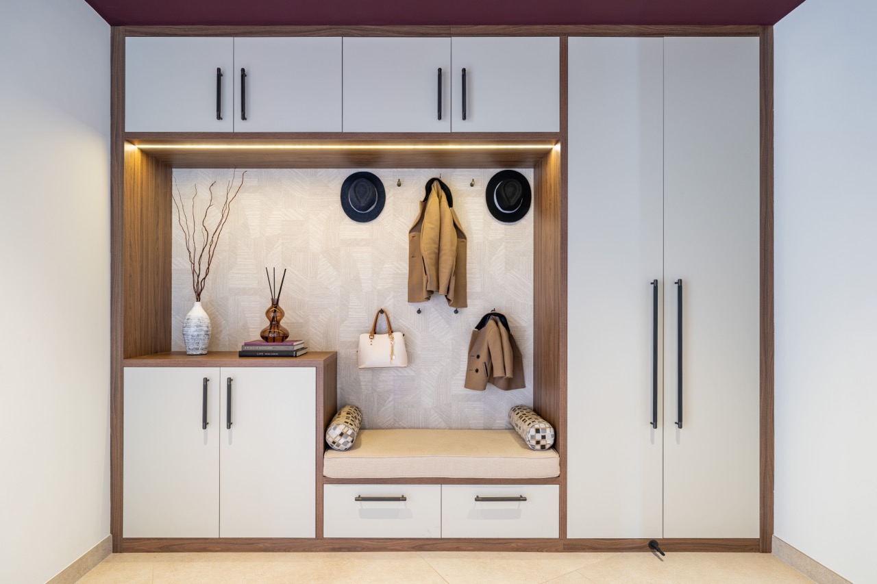 Queens Orchard boot room with bespoke walnut-and-cream fitted joinery, a cushioned bench seat and coat hooks