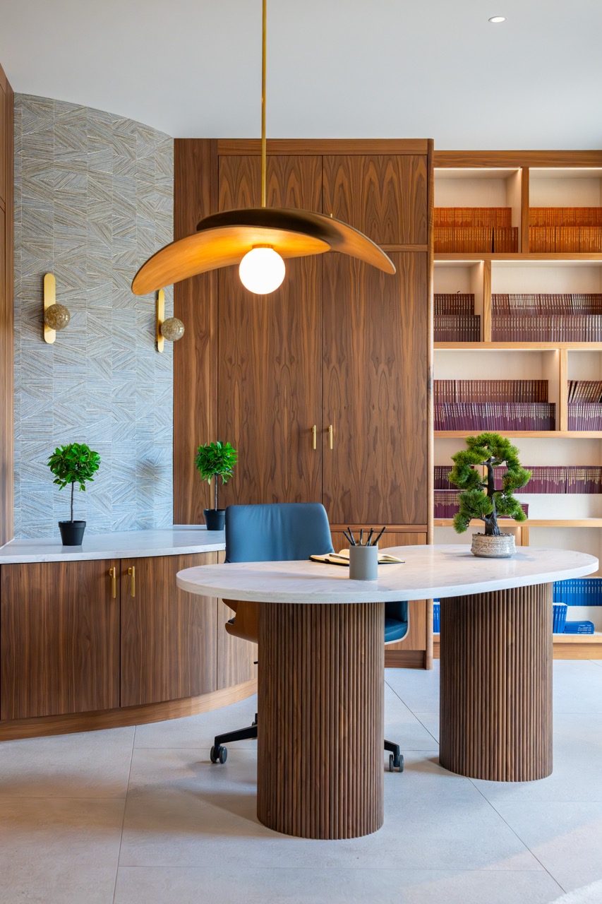 Queens Orchard home office with an oval marble desk on fluted walnut bases, a blue leather chair and fitted library shelving