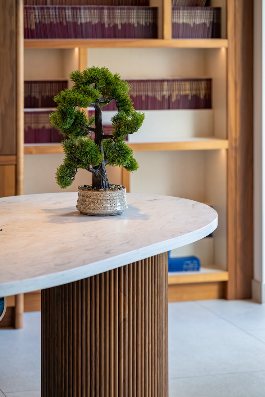 Queens Orchard home office detail with a bonsai on the marble desk and backlit walnut library shelving